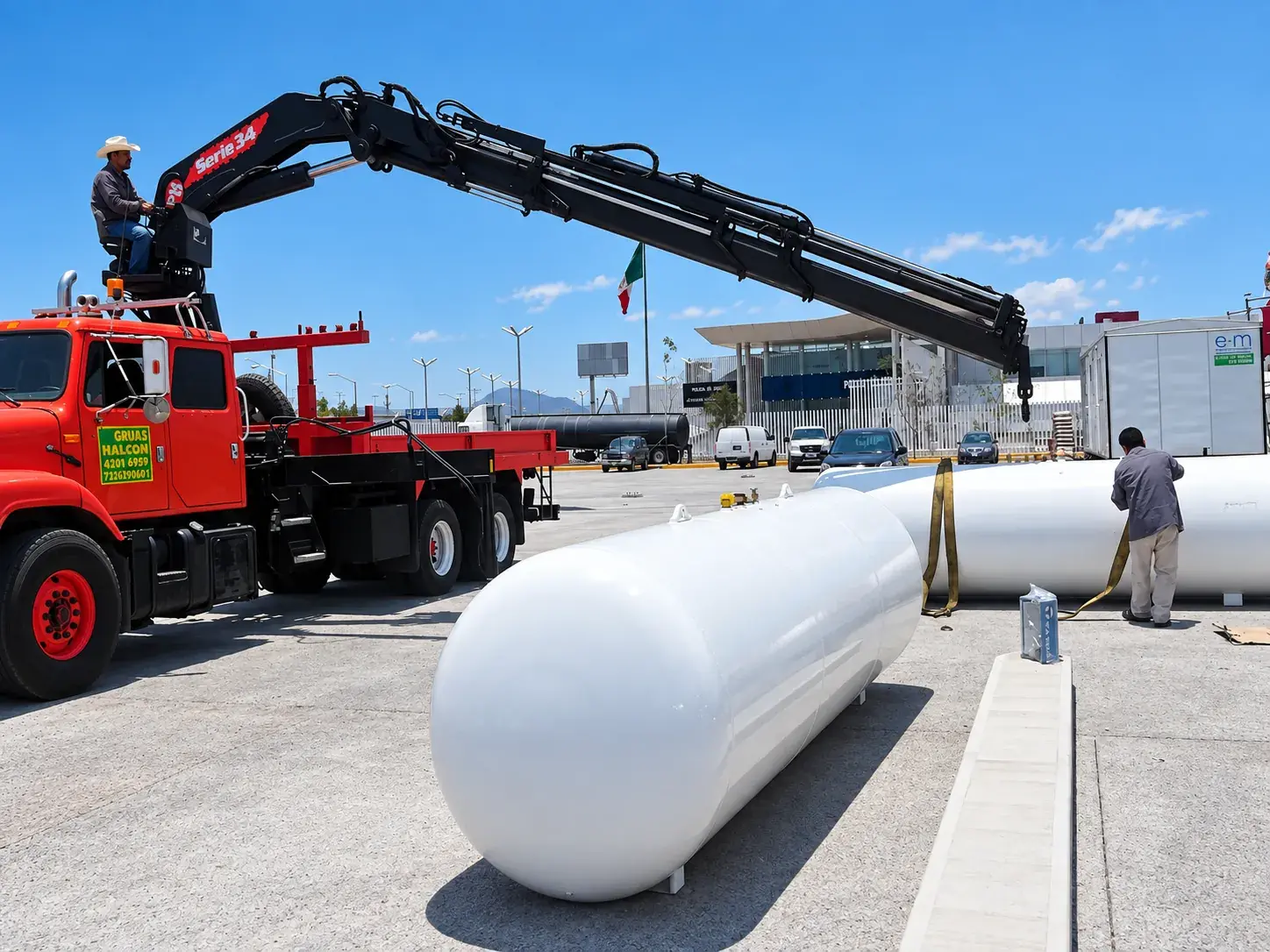 Grúa roja junto a dos tanques estacionarios blancos listos para instalarse