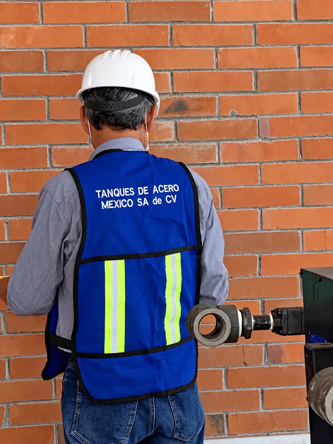 Técnico con casco y chaleco azul de Tanques de Acero México revisando una conexión